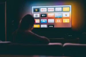 Persona sentada viendo la pantalla de un televisor con muchas aplicaciones de streaming