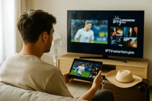 Young man watching IPTV with tablet and TV, fan and suitcase nearby